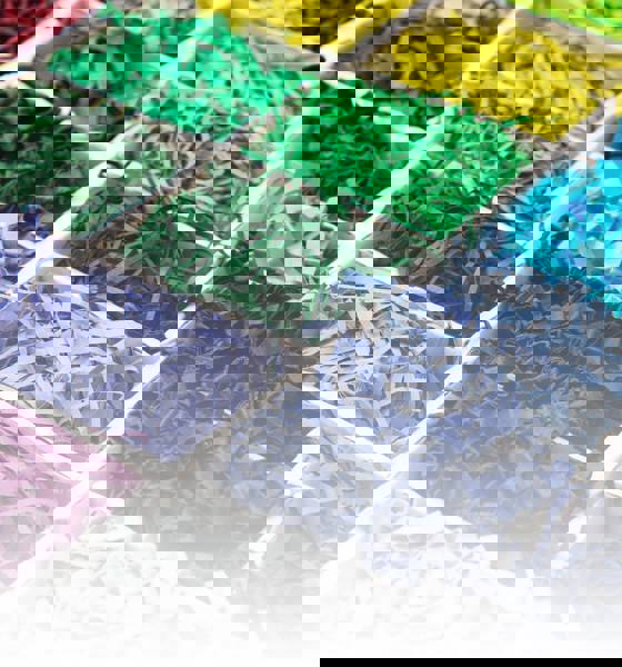 Een collectie levendig gekleurd SizzlePak-papier, gepresenteerd in een doos, met een scala aan kleuren voor decoratief gebruik.