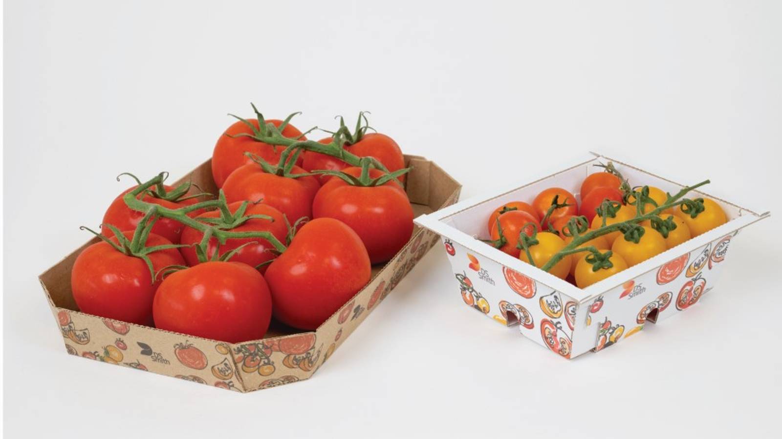 Fresh red and yellow tomatoes displayed in two DS Smith recyclable cardboard produce trays, showcasing packaging formats for retail fruit and vegetable presentation.