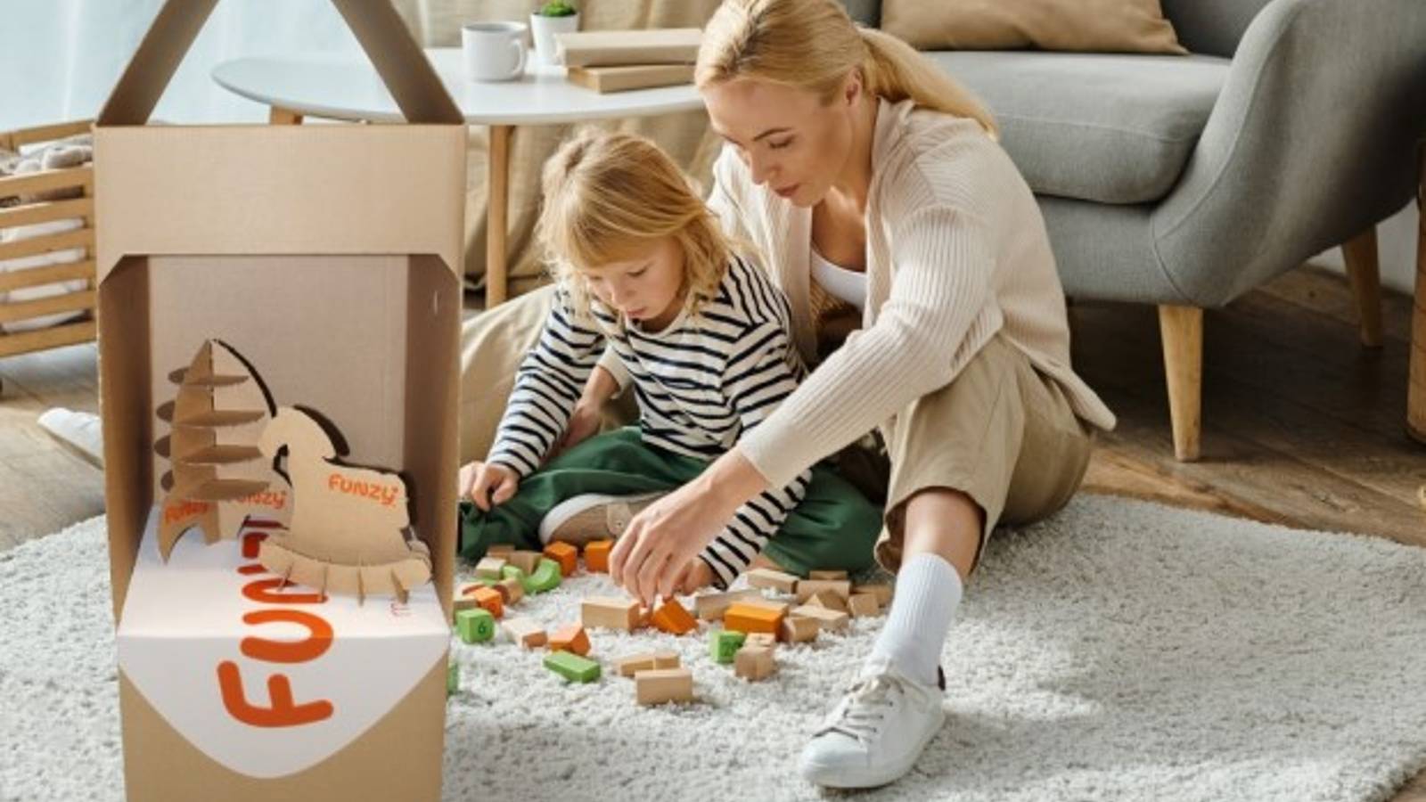 Frau spielt mit Kind neben Funzy Verpackung aus Wellpappe