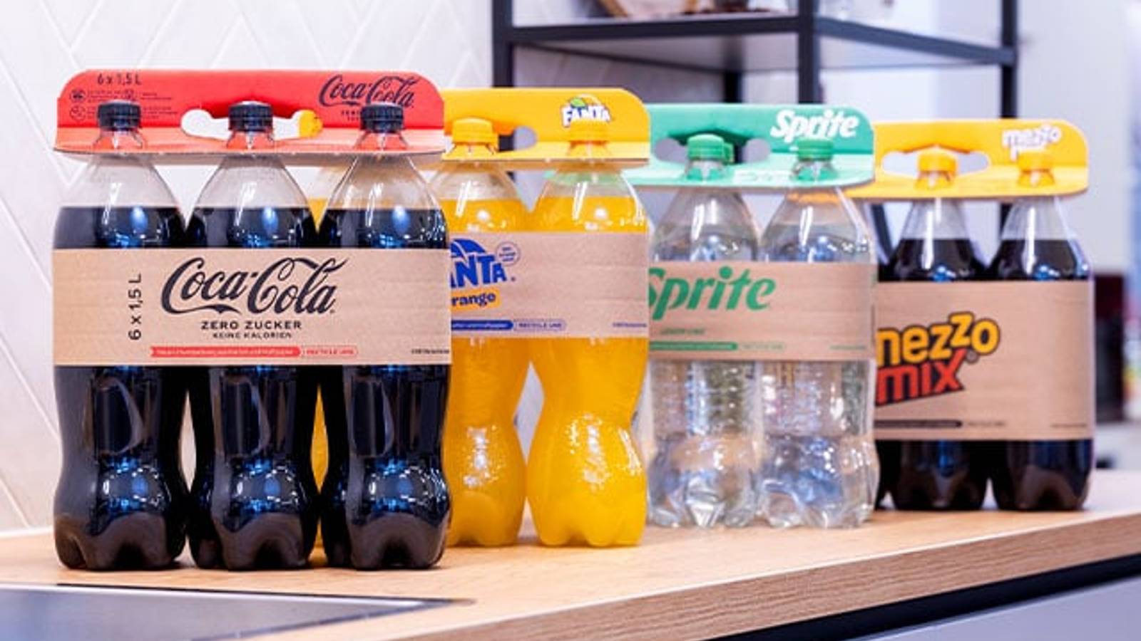 Flessen frisdrank, Coca-Cola, Fanta, Sprite, handvat van golfkarton in supermarktschap
