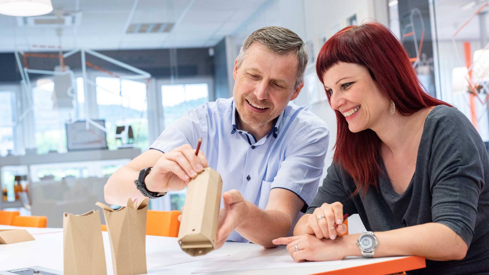 Verpakkingsontwerpers van DS Smith werken samen aan een duurzaam kartonnen verpakkingsprototype in een designstudio.