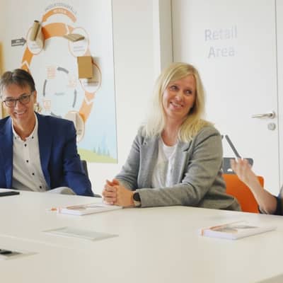 Drei Kolleginnen und Kollegen sitzen gemeinsam am Tisch und unterhalten sich.