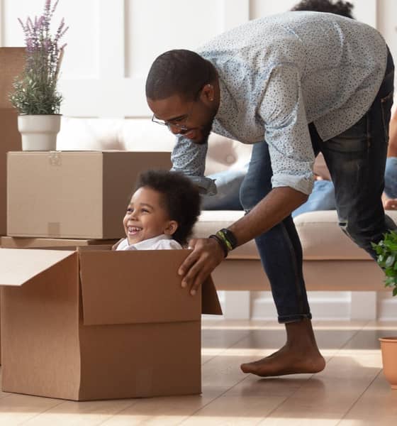 Mann spielt mit Kind in einer Box aus Wellpappe.