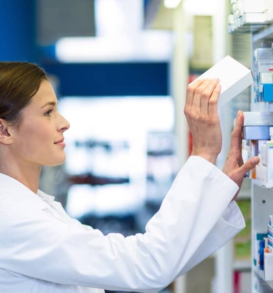 Eine Apothekerin holt eine Verpackung aus dem Regal.