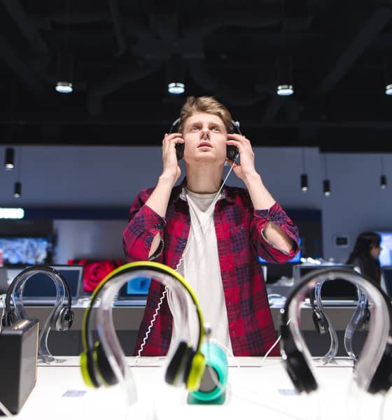 Mann mit Kopfhörern in einem Elektroladen.