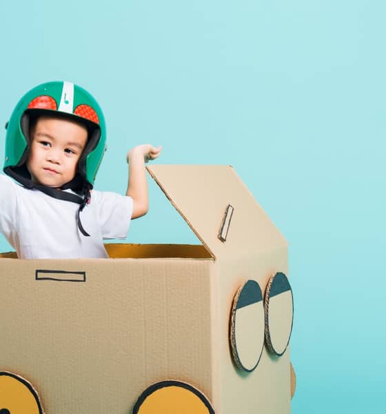 Kleiner Junge spielt in einer Box aus Wellpappe.