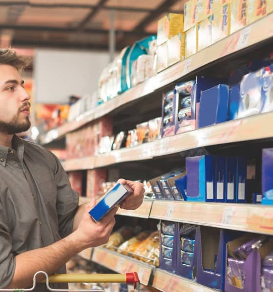 Mann steht im Supermarkt vor einem Regal.