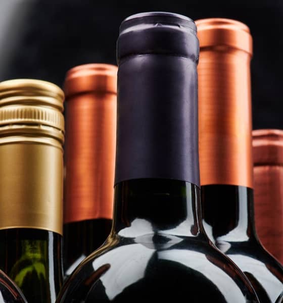 Flaschenhälse von mehreren hintereinanderstehenden Flaschen Wein.