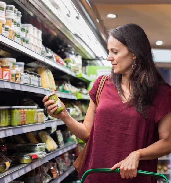 Frau im Supermarkt nimmt ein Produkt aus dem Regal.