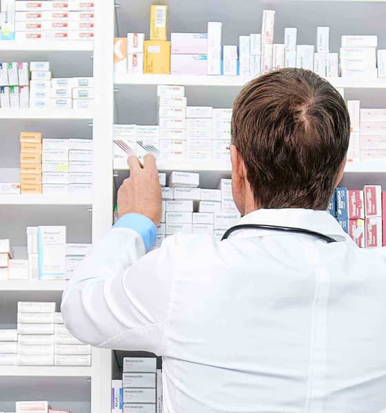 apoteker foran hylder med medicin