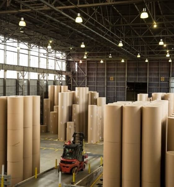 a forklift truck driving through giant reels of paper ina warehouse