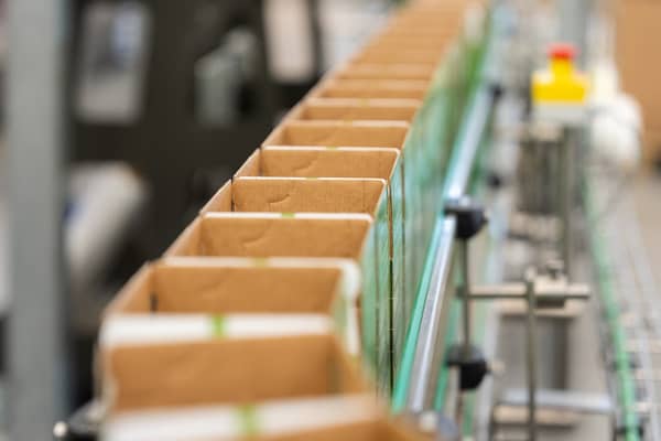 Empty cardboard beverage cartons moving along a production line in a packaging facility.
