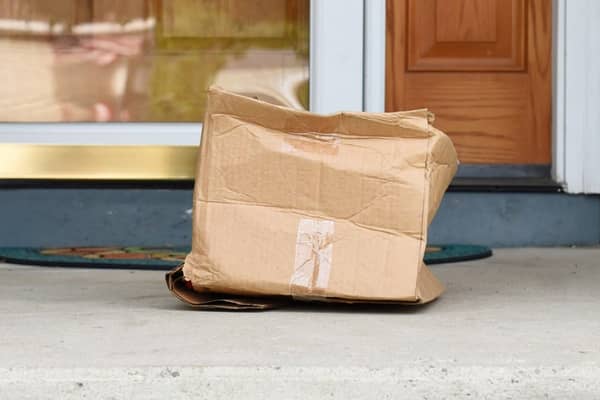 Beschädigte Box aus Wellpappe steht vor dem Haus