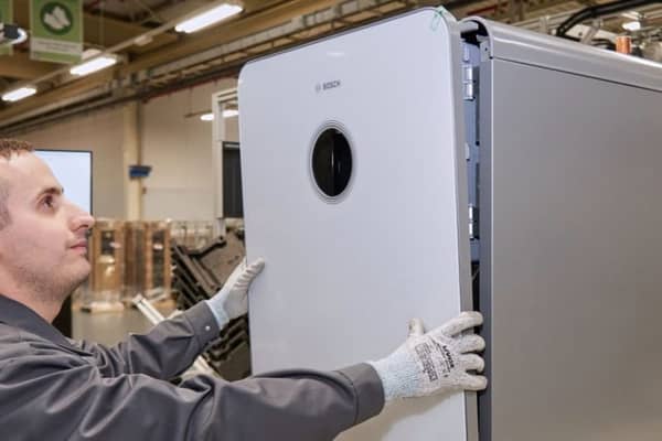 Mitarbeiter in der Produktion arbeitet daran eine weißer Gastherme von Bosch zusammenzusetzen