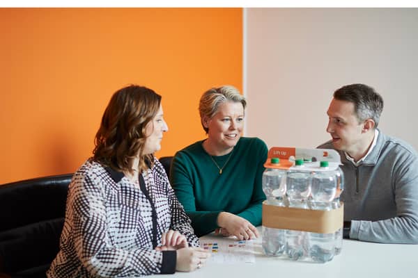 Ihmisiä juomapakkauksen ympärillä