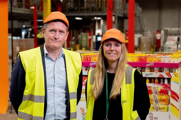 kaksi ihmistä seisoo automaatiolinjojen vieressä ja katsoo kameraan