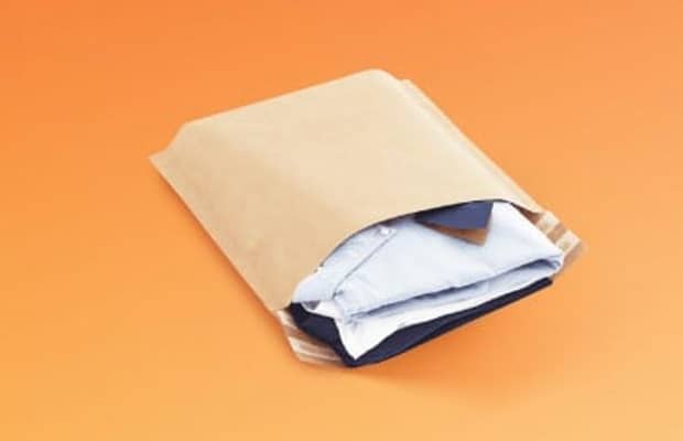 Braune Versandtasche aus Papier mit Bodenfalte gefüllt mit Klamotten.