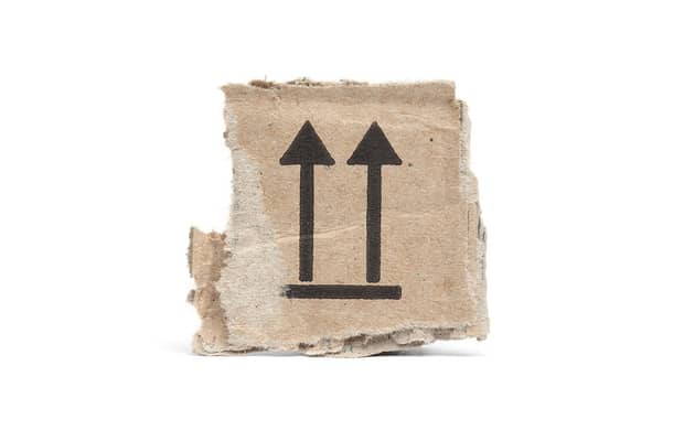 Stukje karton voor recycling, bedrukt met this side up pijlen