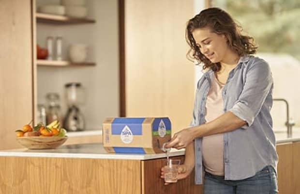 Vrouw tapt water uit bag-in-box in de keuken