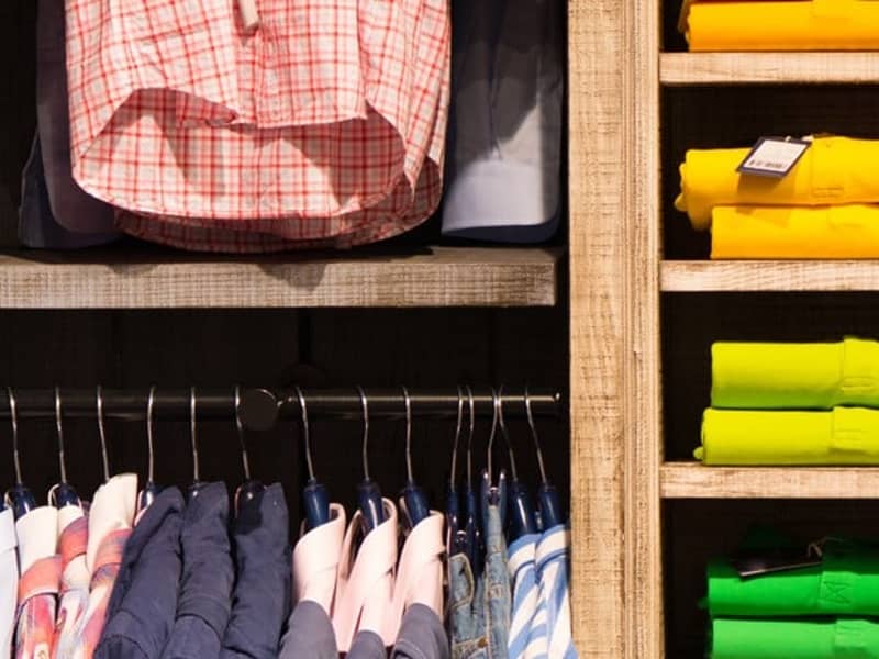 Nahaufnahme eines Kleiderschranks mit aufgehängten bunten Hemden.