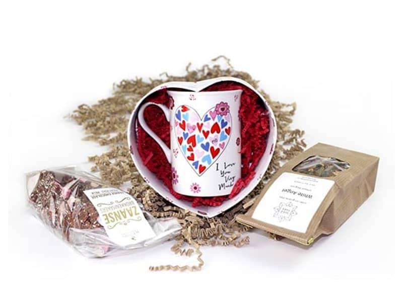 Eine bunte Tasse wird in buntem Füllmaterial verpackt.