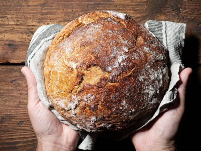 Zwei Hände halten ein gebackenes Brot.