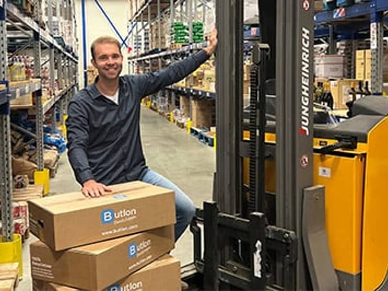 Medewerker Butlon met dozen bij heftruck in magazijn