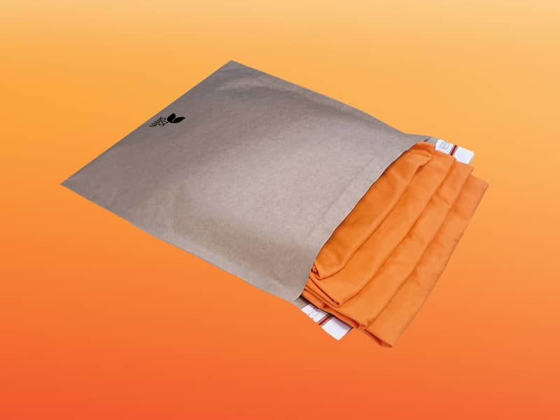 Een bubble envelope gevuld met t-shirts geplaatst op een oranje achtergrond