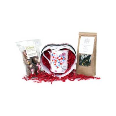 Een geschenkset van een koffiemok, bonbons en een hartvormig doosje met gekleurd sizzlepak opvulmateriaal