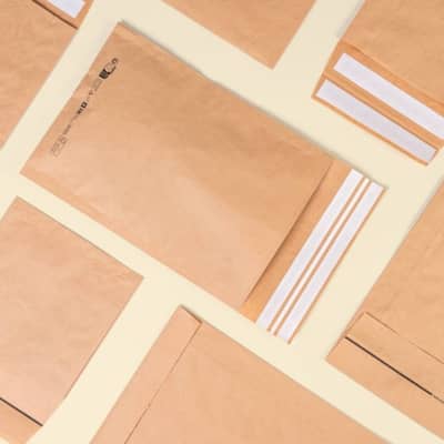 Viele braune unterschiedliche Papierversandtaschen liegen flach auf gelbem Hintergrund nebeneinander und man hat eine Vogelperspektive. 