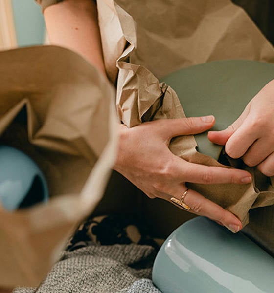 kädet pakkaavat muuttoon tavaraa