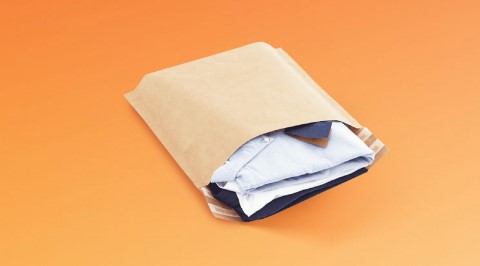 Braune Versandtasche aus Papier mit Bodenfalte gefüllt mit Klamotten.