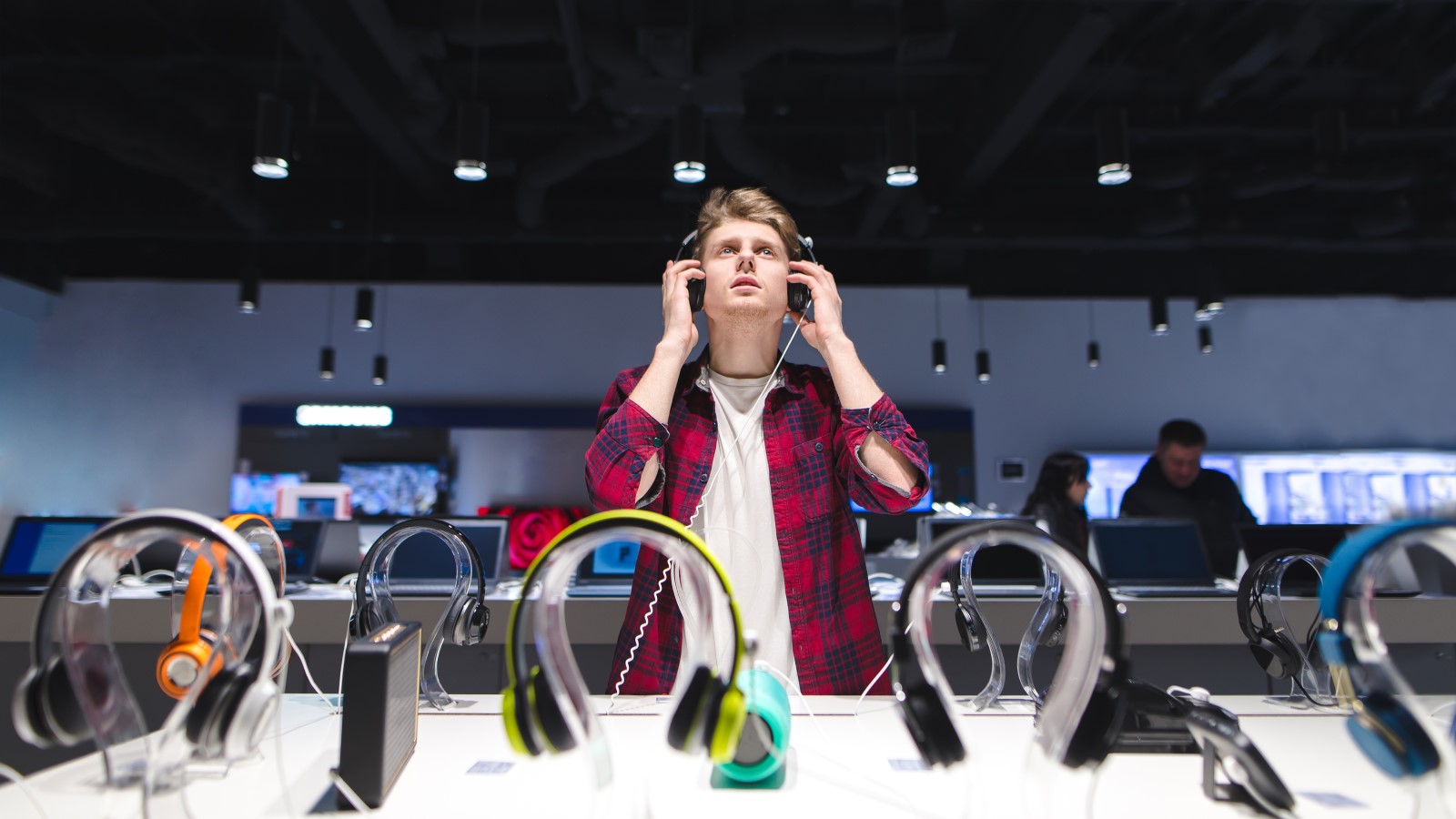 Mann mit Kopfhörern in einem Elektroladen.