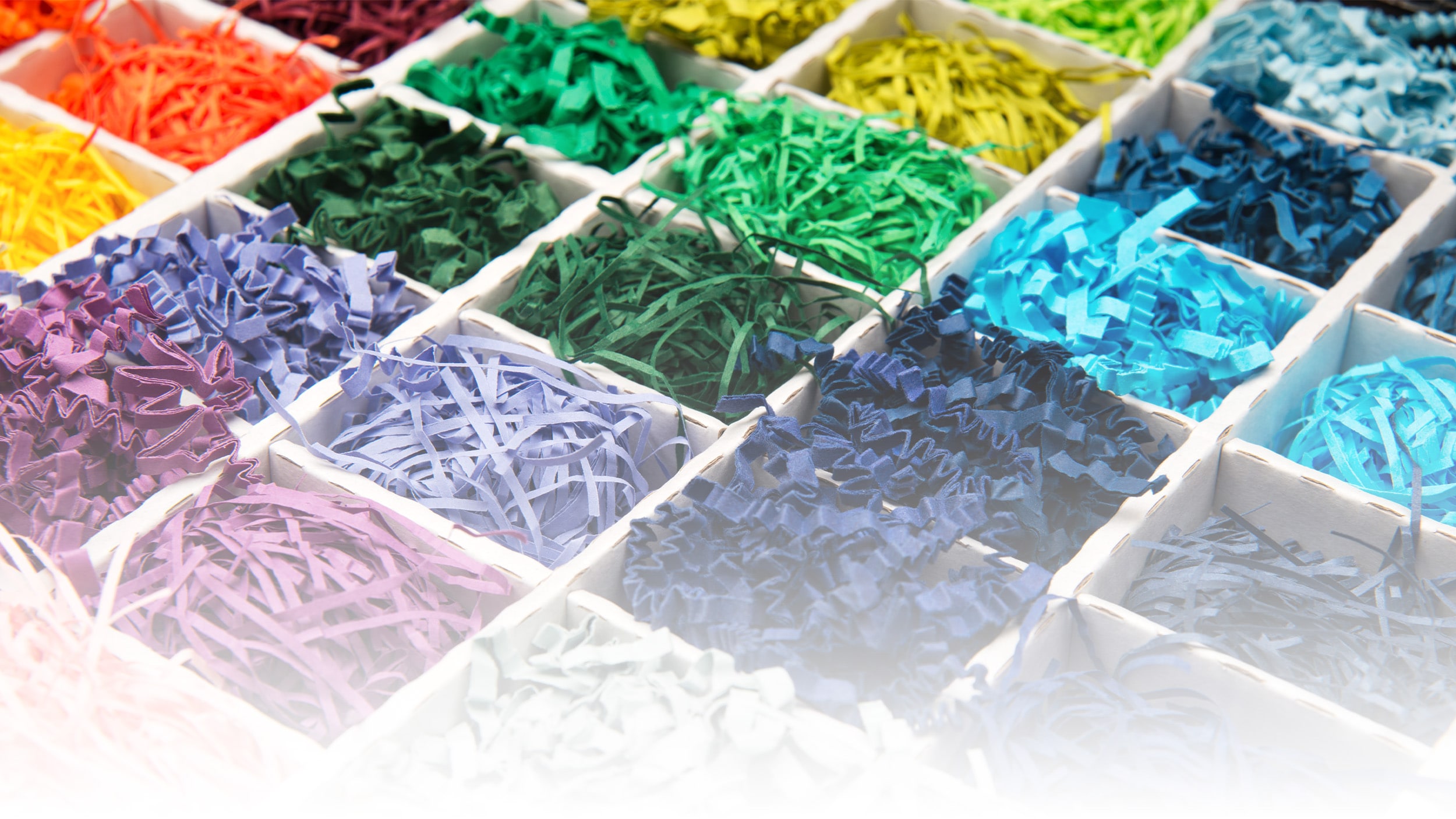 Een collectie levendig gekleurd SizzlePak-papier, gepresenteerd in een doos, met een scala aan kleuren voor decoratief gebruik.