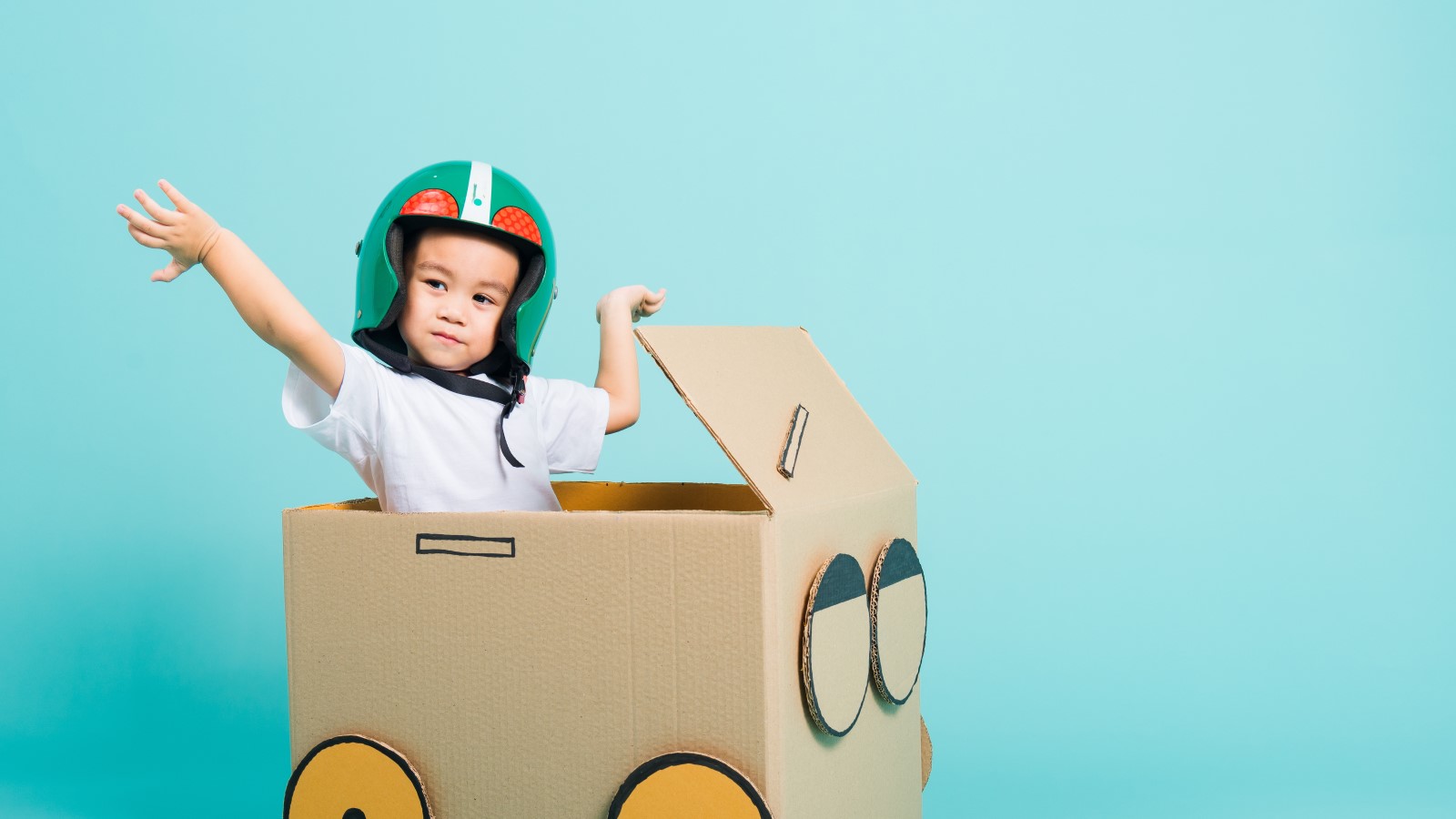 Kleiner Junge spielt in einer Box aus Wellpappe.