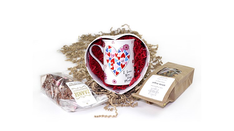 Eine bunte Tasse wird in buntem Füllmaterial verpackt.