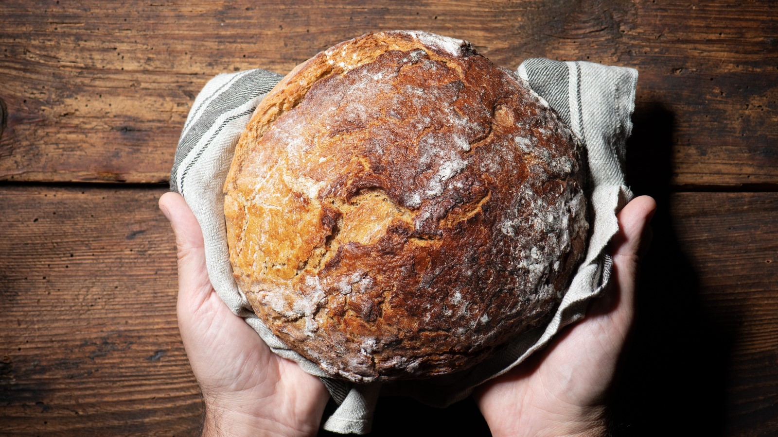 Zwei Hände halten ein gebackenes Brot.