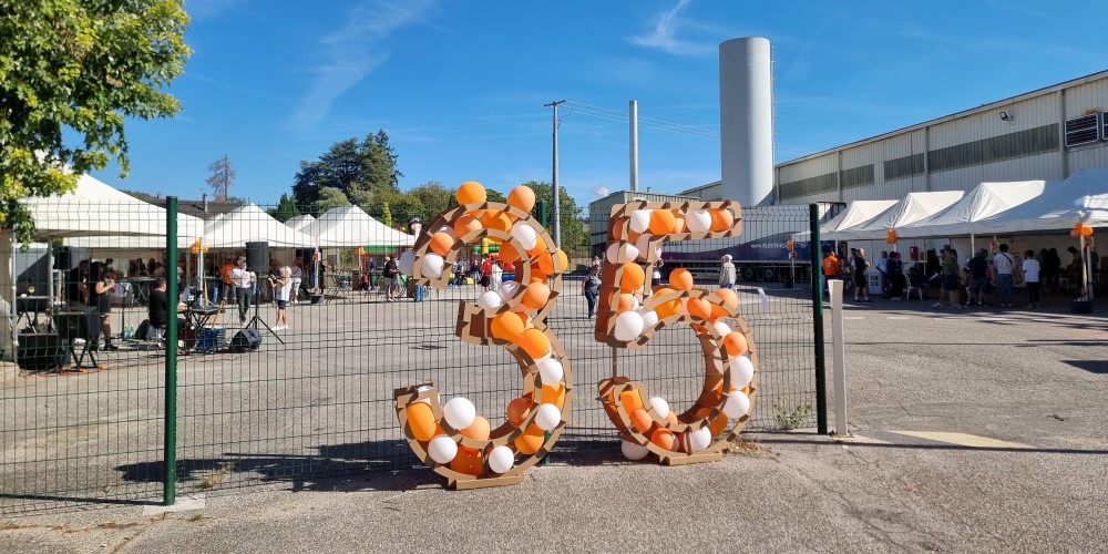 Célébration du 35e anniversaire avec une structure “35” en ballons orange et blancs devant un site industriel