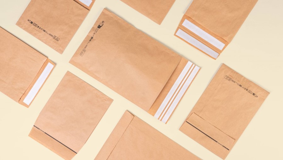 Viele braune unterschiedliche Papierversandtaschen liegen flach auf gelbem Hintergrund nebeneinander und man hat eine Vogelperspektive. 