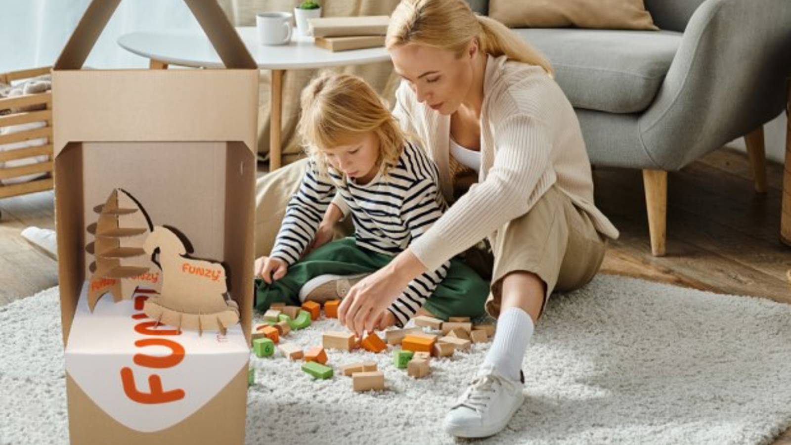 Frau spielt mit Kind neben Funzy Verpackung aus Wellpappe