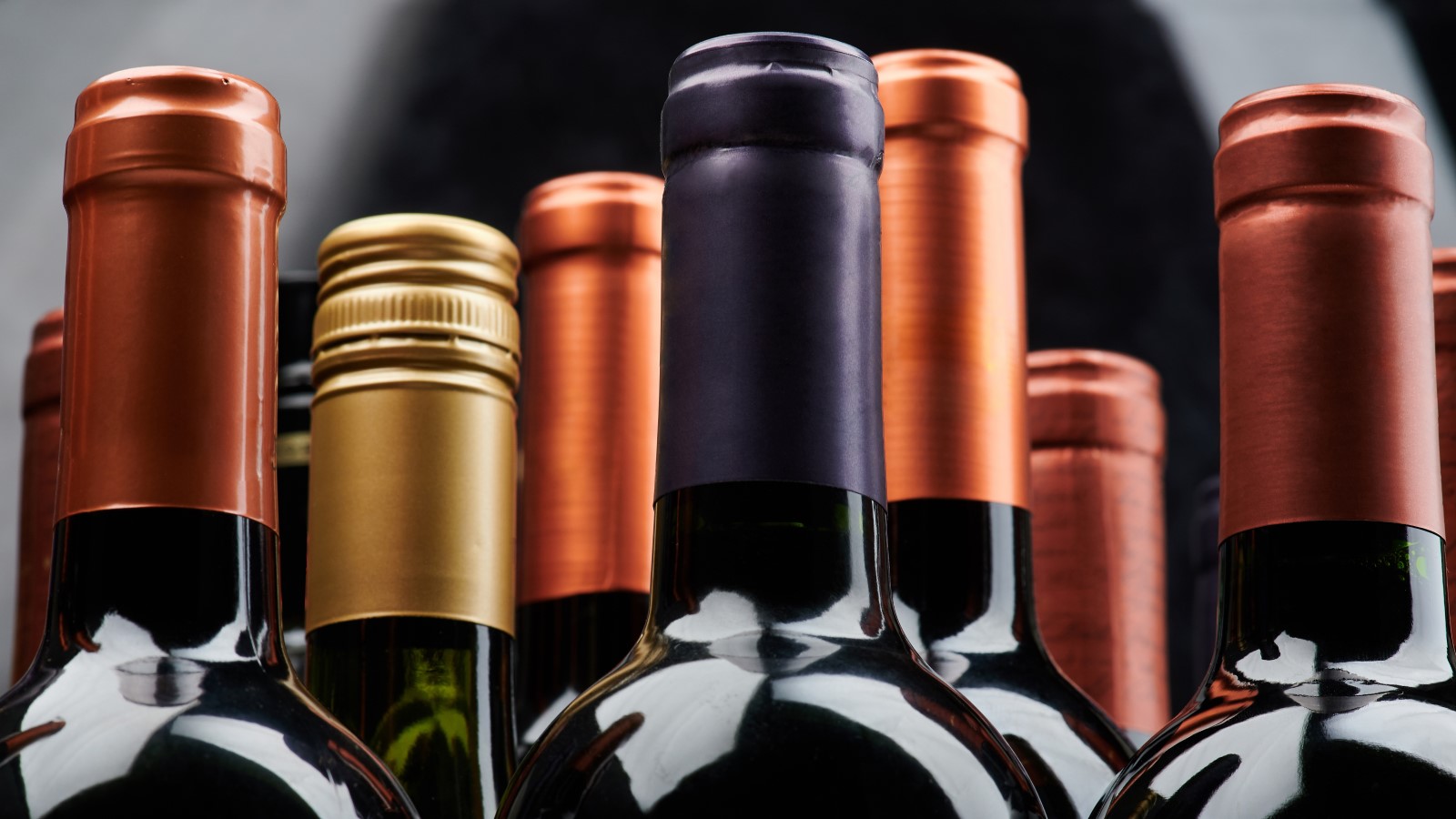 Flaschenhälse von mehreren hintereinanderstehenden Flaschen Wein.