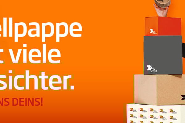 junge blonde Frau in dunklem Kleid steht rechts von einem Wellpappaufsteller und hält einen kleinen Wellpappkarton in der Hand und lächelt.