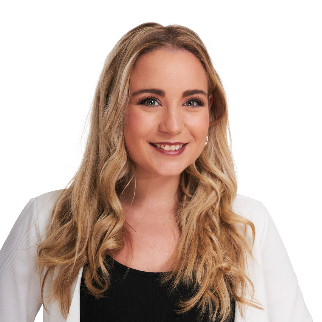 Portrait einer jungen Frau mit langen blonden Haaren, dunkles T-Shirt mit einem weißen Jäckchen drüber. Sie lächelt in die Kamera.