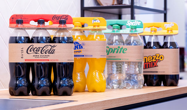 Flessen frisdrank, Coca-Cola, Fanta, Sprite, handvat van golfkarton in supermarktschap