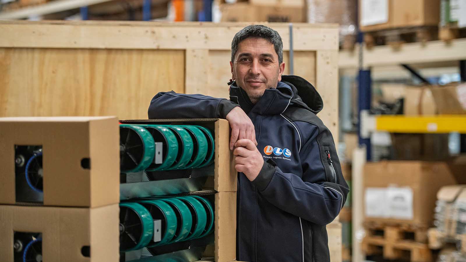 DLS magazijn medewerkers, staand leunend bij machineonderdelen , ingepakt in karton