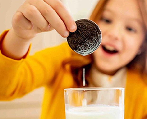 Girl dipping Oreo cookie in milk